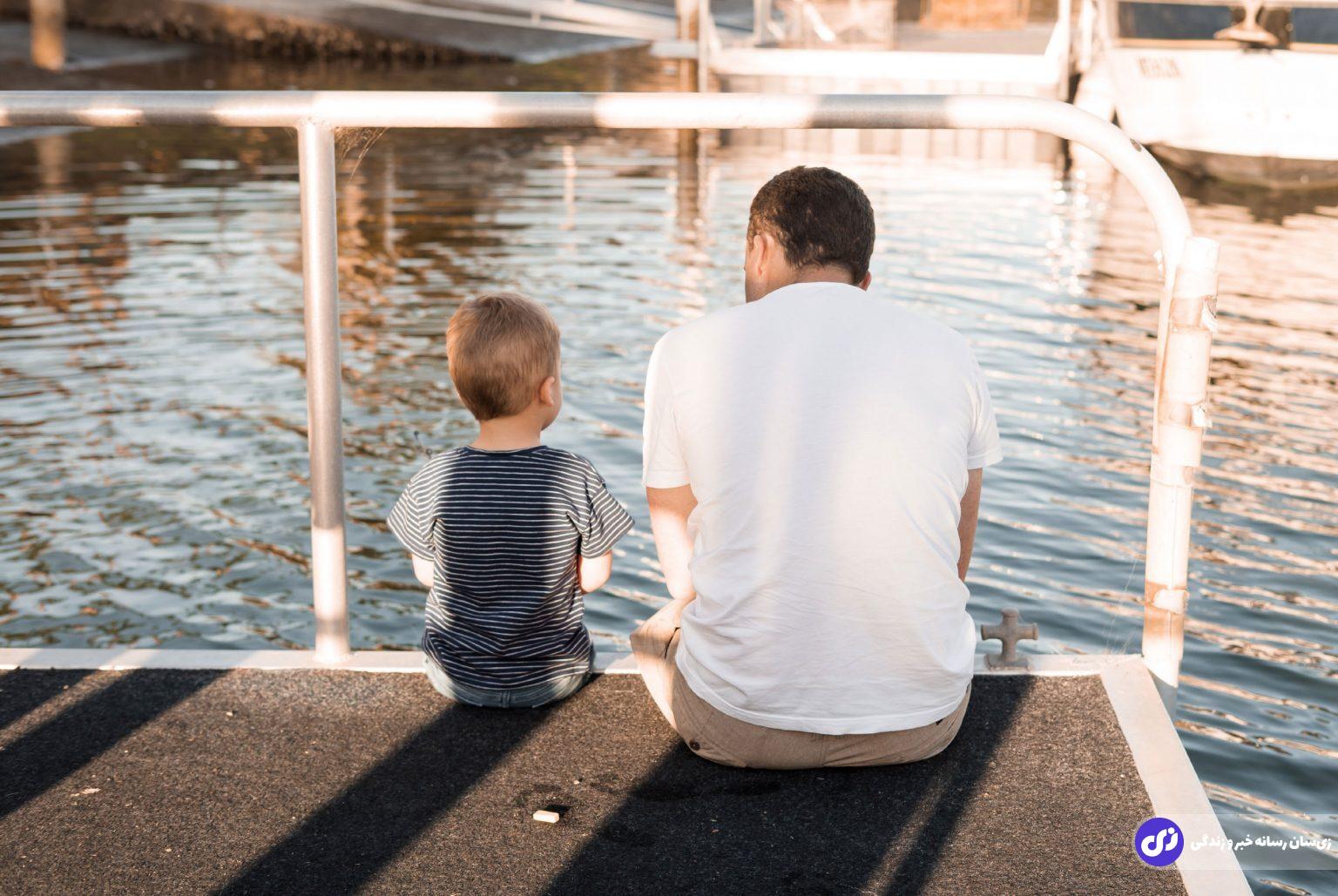 عکس برای تبریک روز پدر یک پدر و پسر نشسته در کنار یک دریاچه