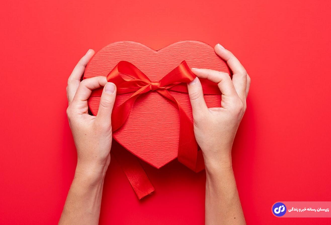 دختری در حال درست کردن کادو ولنتاین در جعبه ای به شکل قلب