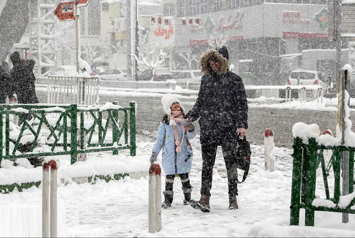 مردی با دخترش در زیر بارش شدید برف راه می رود