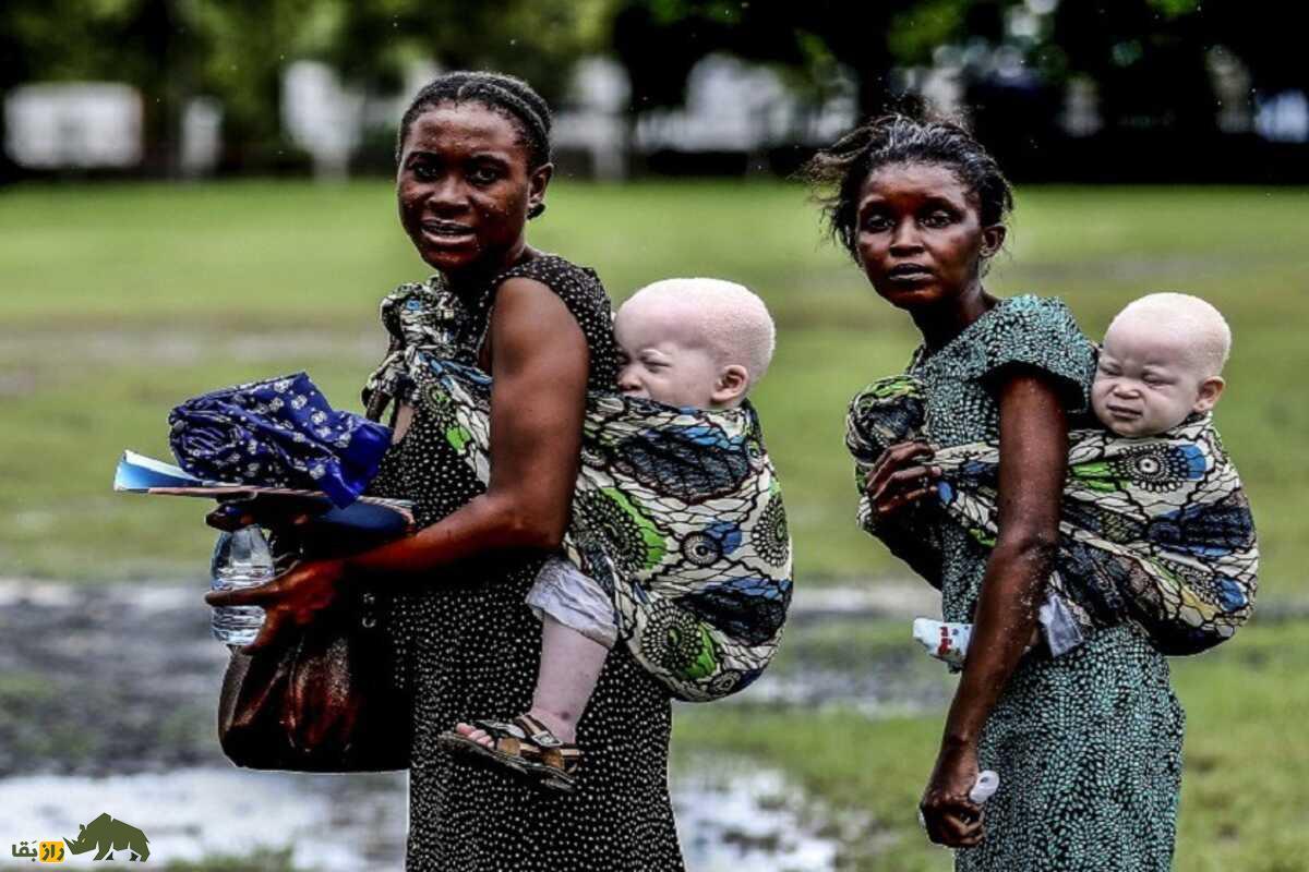 دو زن سیاه پوست در آفریقا که دو کودک زال خود را به پشت کمر بسته اند